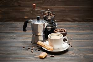 Timemore-Kaffeemühle-Test: Ansicht einer Kaffeemühle voller Kaffeebohnen, die hinter einer Tasse steht. 