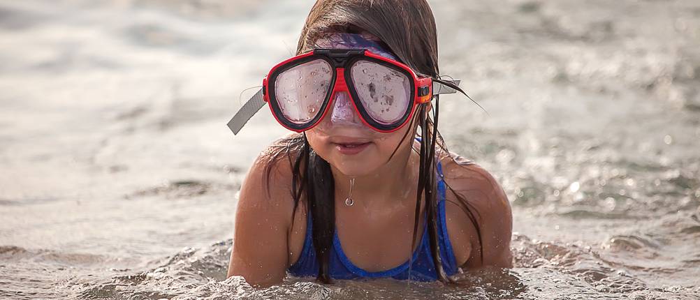 antibeschlag-test: junges Mädchen im Meer, trägt eine rote Taucherbrille mit beschlagenen Gläsern