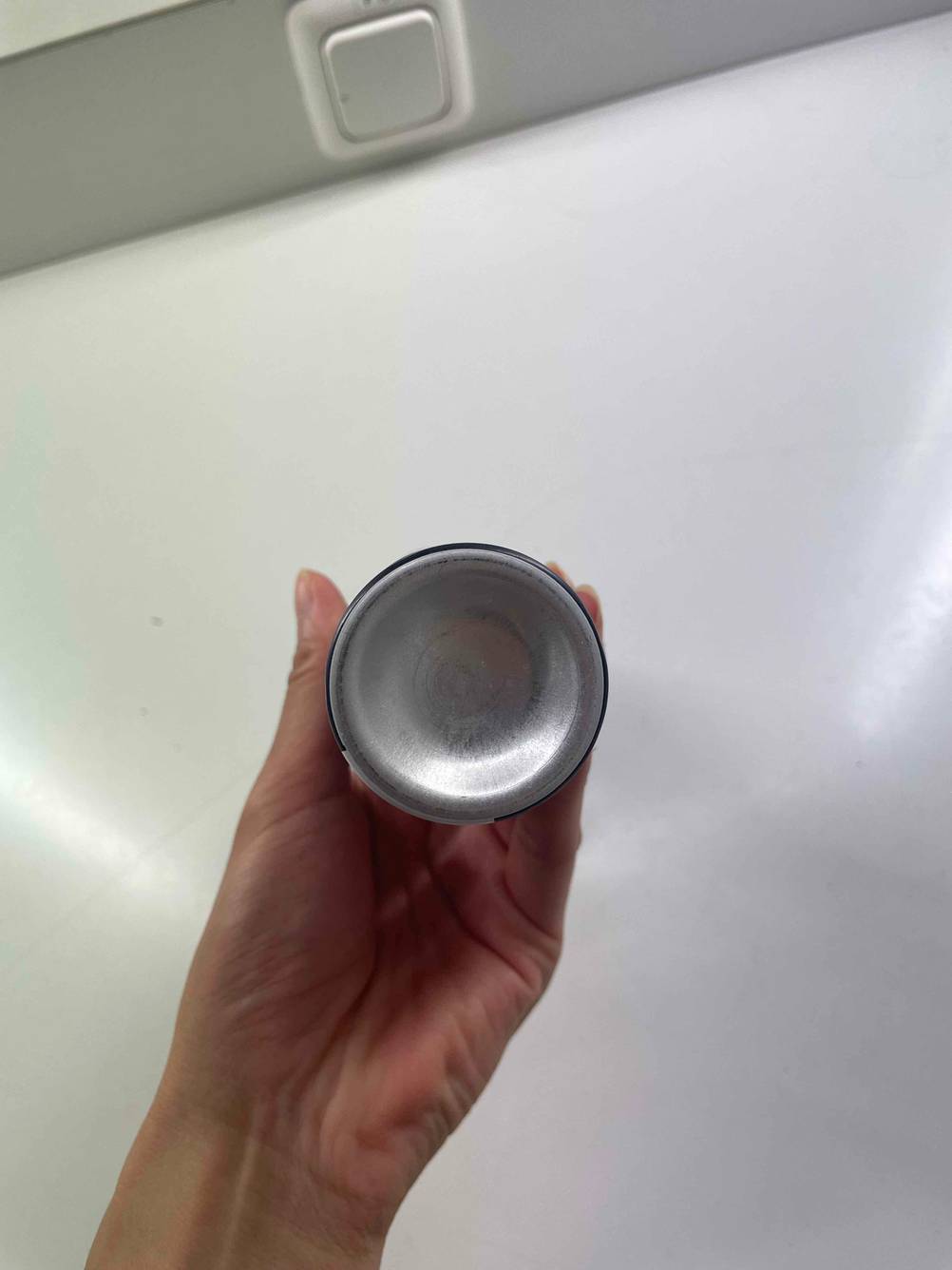 Der Boden einer Dose des getesteten Antistatik-Sprays von einer Hand hochgehalten.