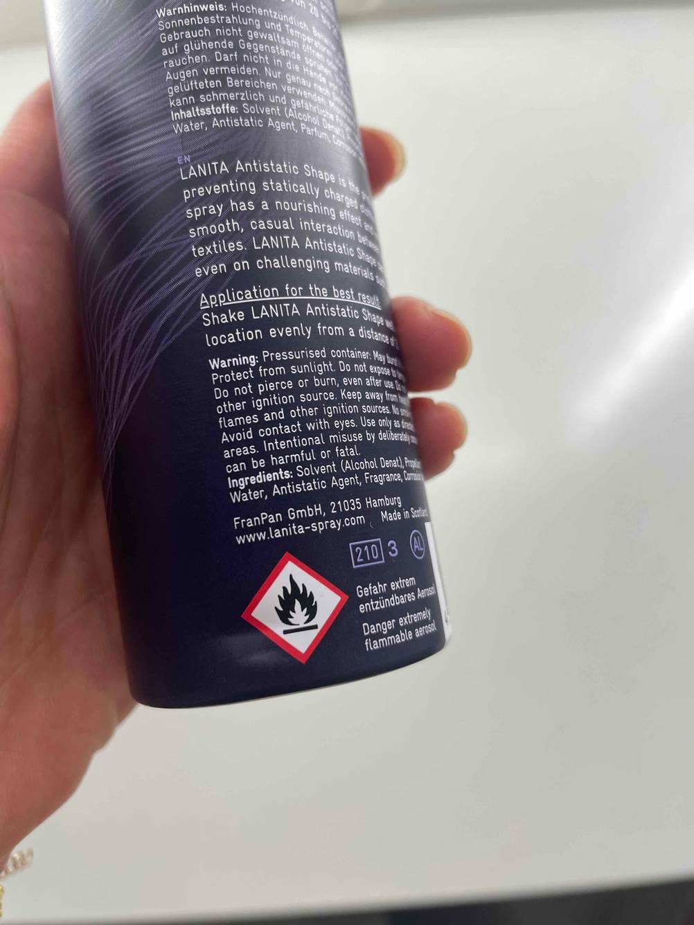 Rückseite einer Dose Antistatik-Sprays im Test mit Warnhinweisen von einer Hand gehalten.