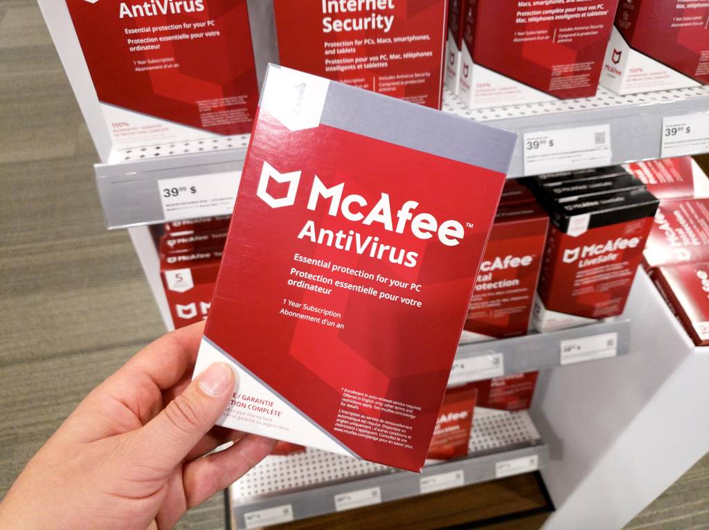Eine Person hält eine Produktverpackung von McAfee Antivirus in der Hand.