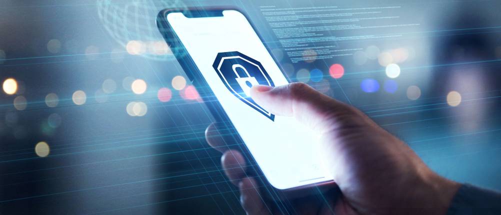 Antivirus-App-Test: Eine Person hält ein Smartphone in der Hand und drückt mit dem Daumen auf ein Schloss-Symbol auf dem Display.