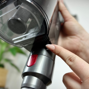 Eine Hand drückt die Entriegelungstaste am Staubbehälter des Anyson Stars 5. Der Filterbereich des Staubsaugers ist deutlich zu sehen.