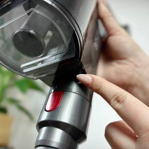 Eine Hand drückt die Entriegelungstaste am Staubbehälter des Anyson Stars 5. Der Filterbereich des Staubsaugers ist deutlich zu sehen.