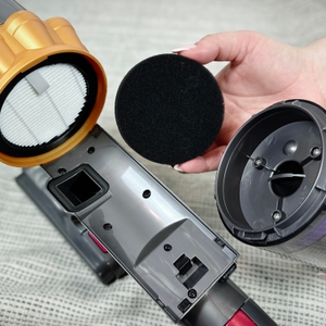 Die Einzelteile des Filtersystems vom Anyson Stars 5 sind ausgebaut. Eine Hand hält den schwarzen Schaumstofffilter.