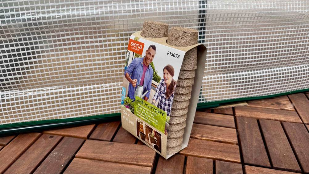 Eine Packung der getesteten Anzuchttöpfe vor einer transparenten Folie auf dem Boden.