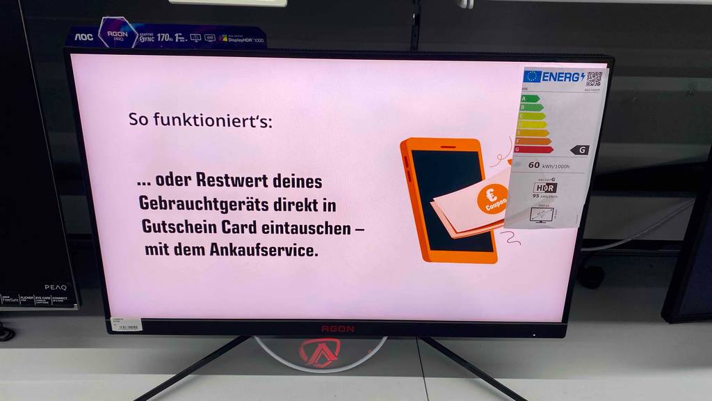 Gaming-Monitor-Test: ein eingeschaltetes AGON-Modell inklusive Energieeffizienzlabel steht in einem Verkaufsbereich.