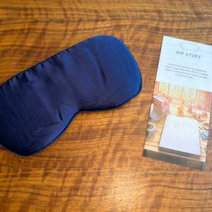 Die Aosun-Seiden-Schlafmaske liegt neben ihrer Beschreibung auf einem Tisch.