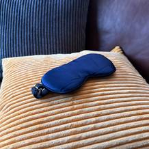 Die Aosun-Seiden-Schlafmaske liegt auf einem Kissen.