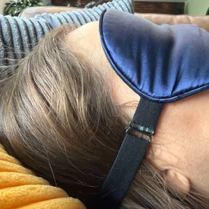 Eine Person liegt mit der Aosun-Seiden-Schlafmaske auf einem Kissen.