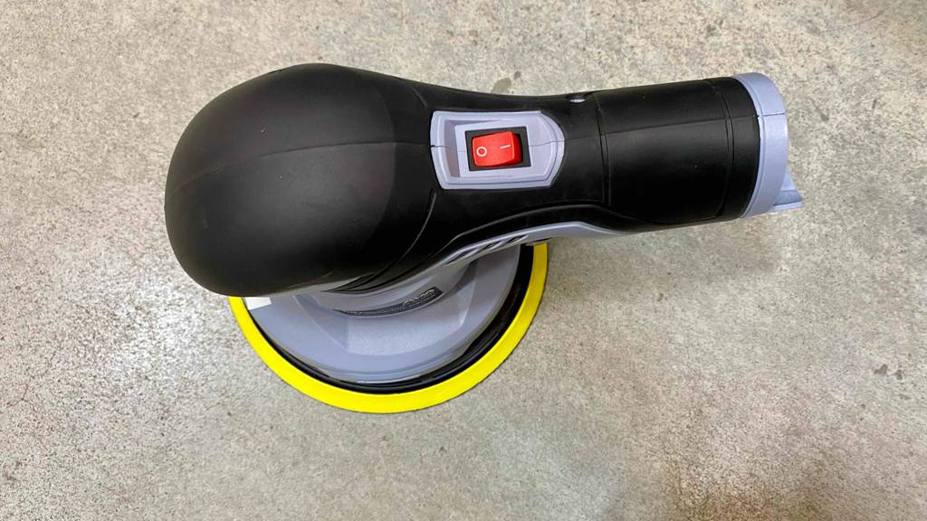 Ansicht von oben auf den schwarzen, gummierten Handgriff mit roter Einschalttaste einer Akku-Poliermaschine im Test.