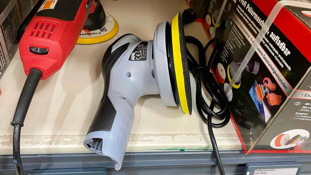 Seitenansicht auf eine im Verkaufsregal liegende, hellgraue Akku-Poliermaschine im Test.