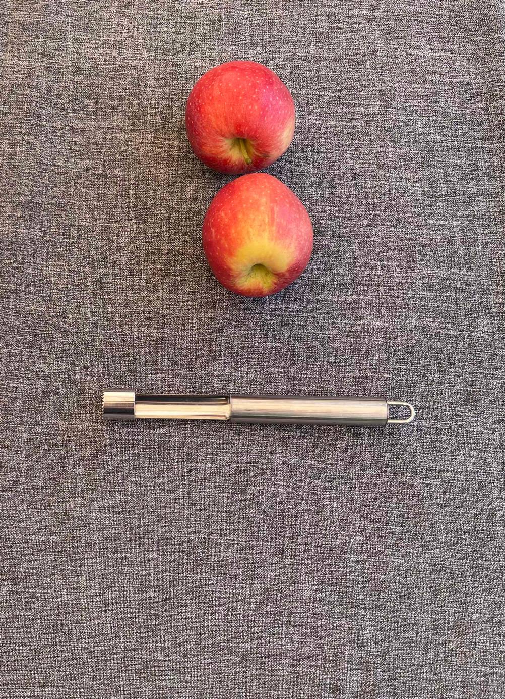 Ein getesteter Apfelausstecher liegt vor zwei Äpfeln.