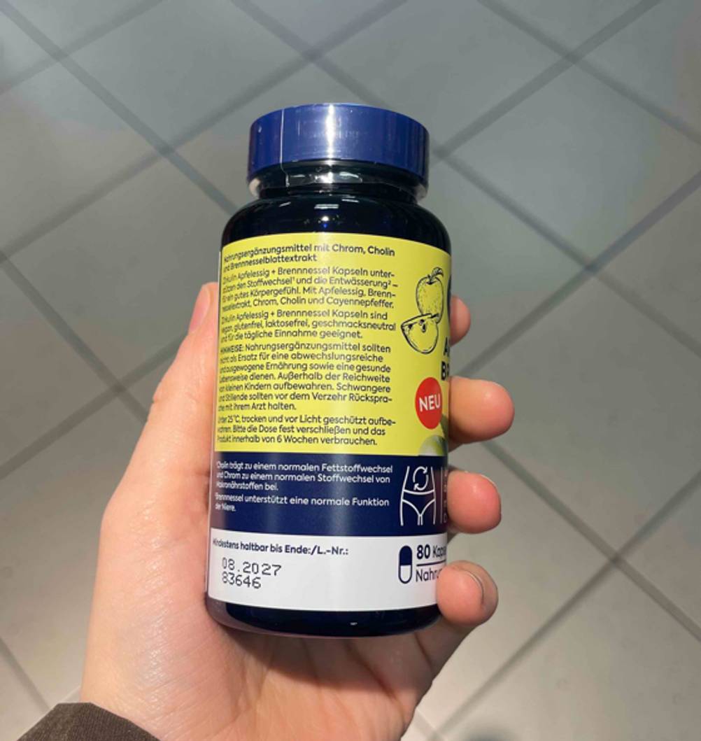 Nahaufnahme der Produktbeschreibung auf dem gelben Etikett auf der lichtdichten Kunststoffdose mit den Apfelessig-Kapseln im Test.