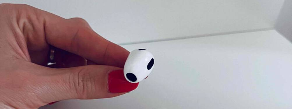 Eine Damenhand hält einen getesteten In-Ear-Kopfhörer mit Mikrofon.
