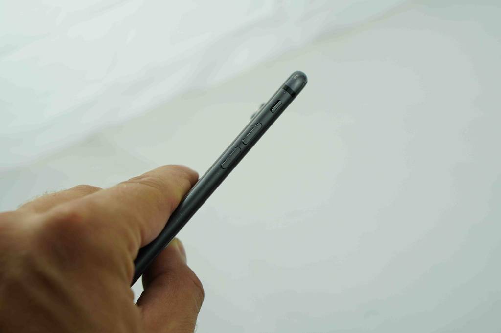 Schwarzes Smartphone im Test wird von Hand hochgehalten, mit Fokus auf die seitlichen Tasten.