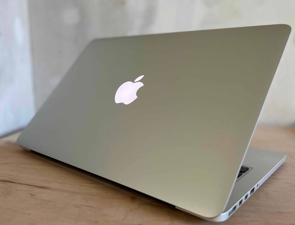Im Test: Ein leicht geöffnetes Apple MacBook von schräg hinten mit leuchtendem Apple Logo.