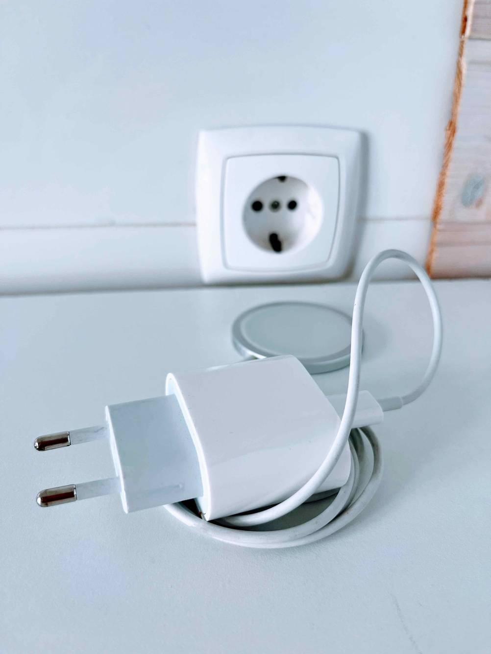 Magnet-Ladekabel im Test: Ein aufgerolltes Kabel von Apple liegt vor einer Steckdose auf weißer Fläche.