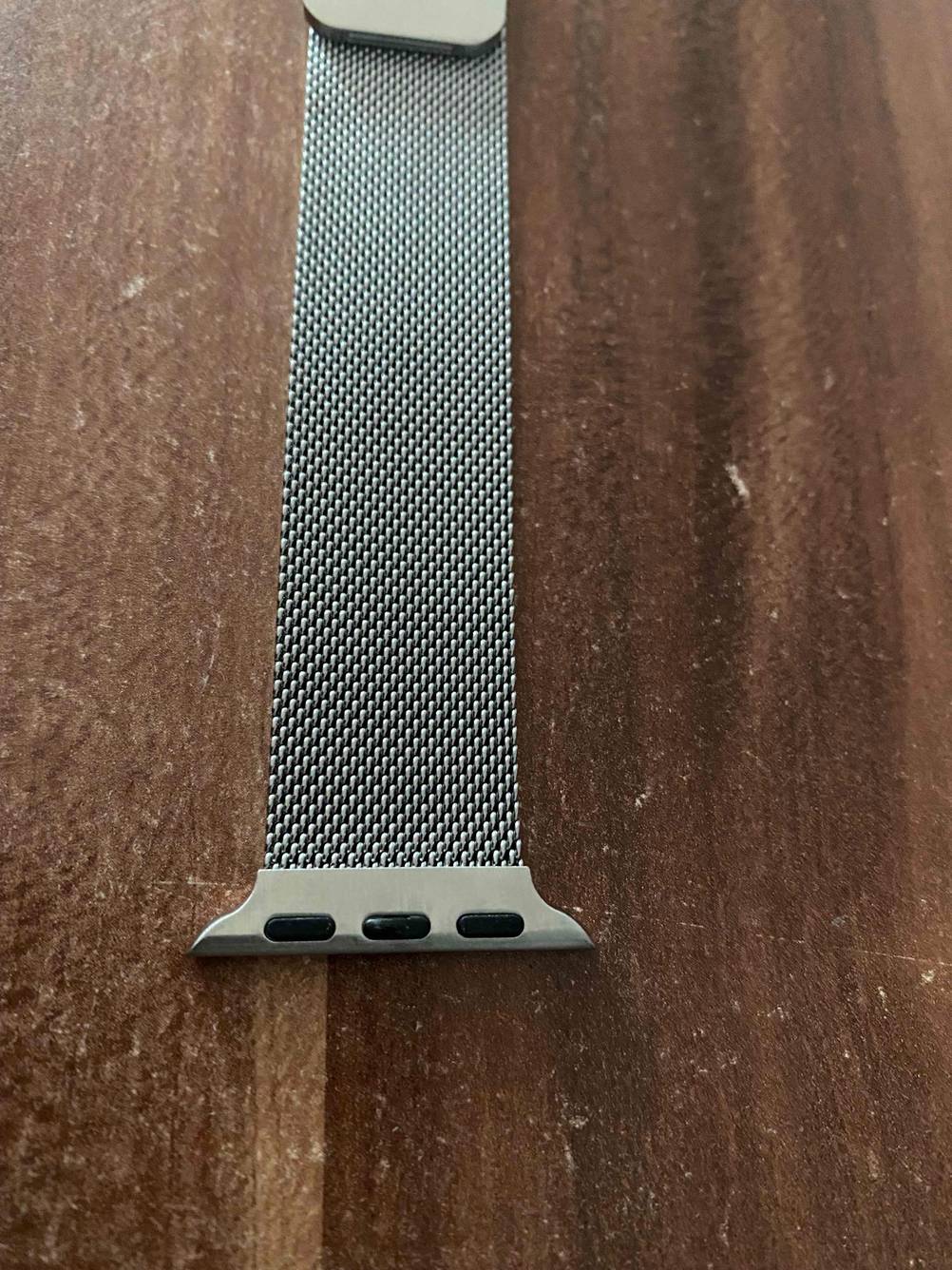 Nahaufnahme des Connectors eines getesteten Apple-Watch-Armbandes auf einer Holzfläche.