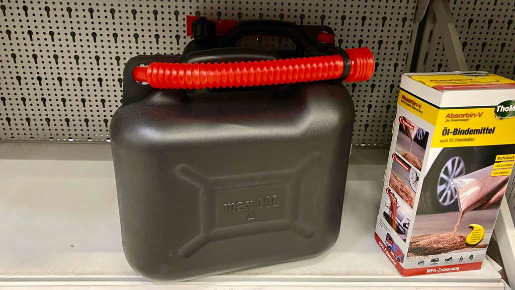 Im Test: Ein 10 l Benzinkanister steht neben Öl-Bindemittel in Regal.