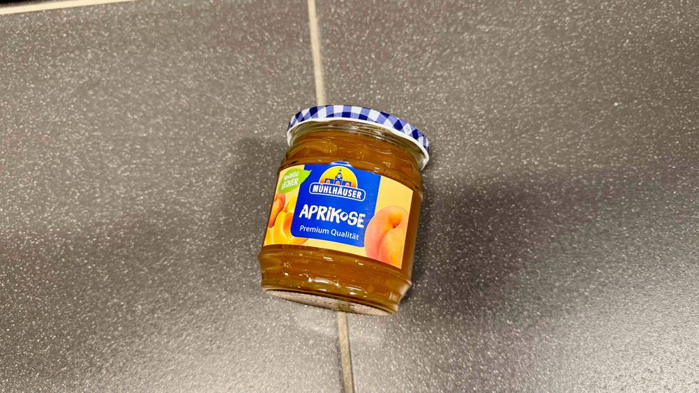 Aprikosenmarmelade getestet: Ein Glas liegt auf einem grauen Boden.