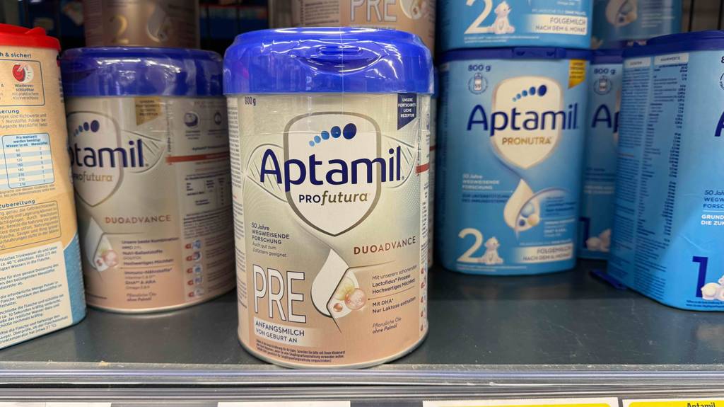 Aptamil-Babynahrung im Test: Mehrere Dosen unterschiedlicher Sorten stehen in einem Regal.