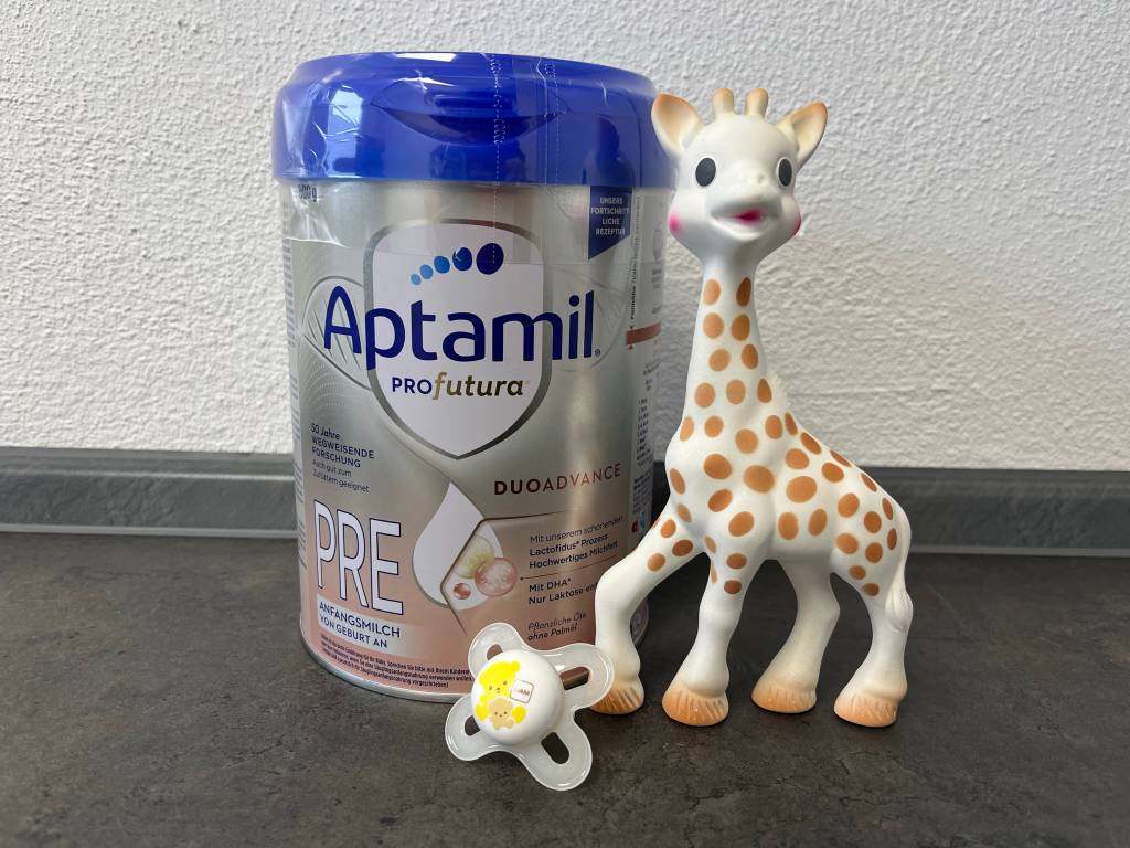 Pre-Nahrung neben einem Schnuller und einer Plüsch-Giraffe