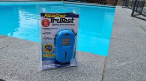 AquaChek Pooltester steht vor einem Pool