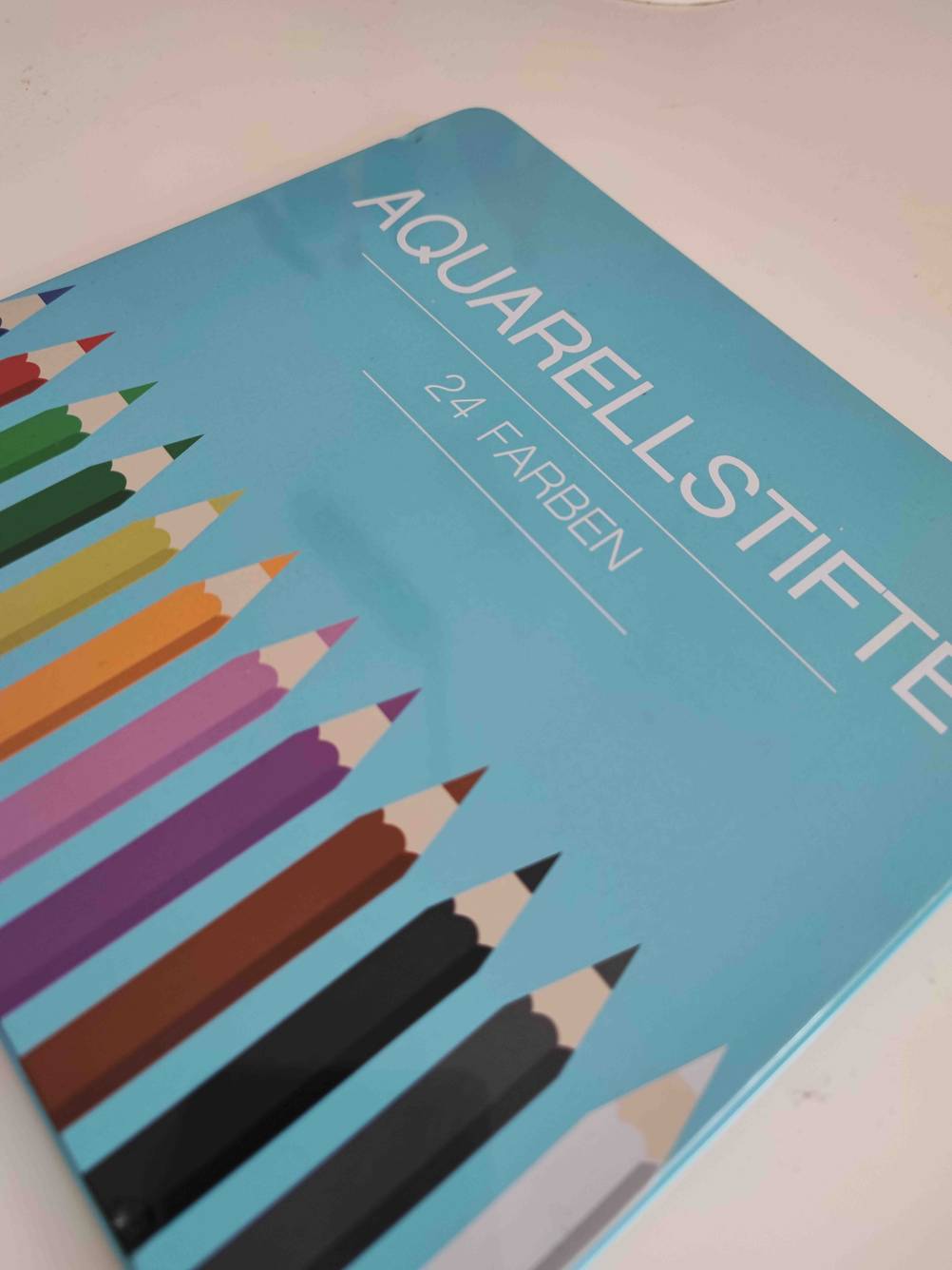 Nahaufnahme einer Box getesteter Aquarellstifte auf einer hellen Fläche.