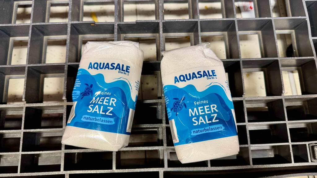 Zwei Packungen Meersalz liegen zum Testen auf einem Metallgitter.