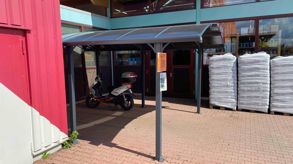 Im Test: Seitenansicht eines Carports, der vor einem Geschäft aufgebaut ist.