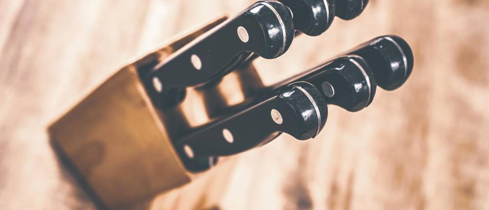 Arcos-Messer im Test: sechs Messer mit schwarzen Griffen in einem Messerblock aus Holz.