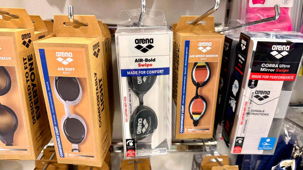 Arena-Schwimmbrille im Test: Mehrere verpackte Brillen in unterschiedlichen Ausführungen hängen in einem Regal.