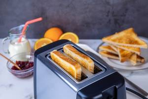 Arendo-Toaster-Test: Ein Toaster mit zwei Toast-Scheiben steht auf einem Frühstückstisch.