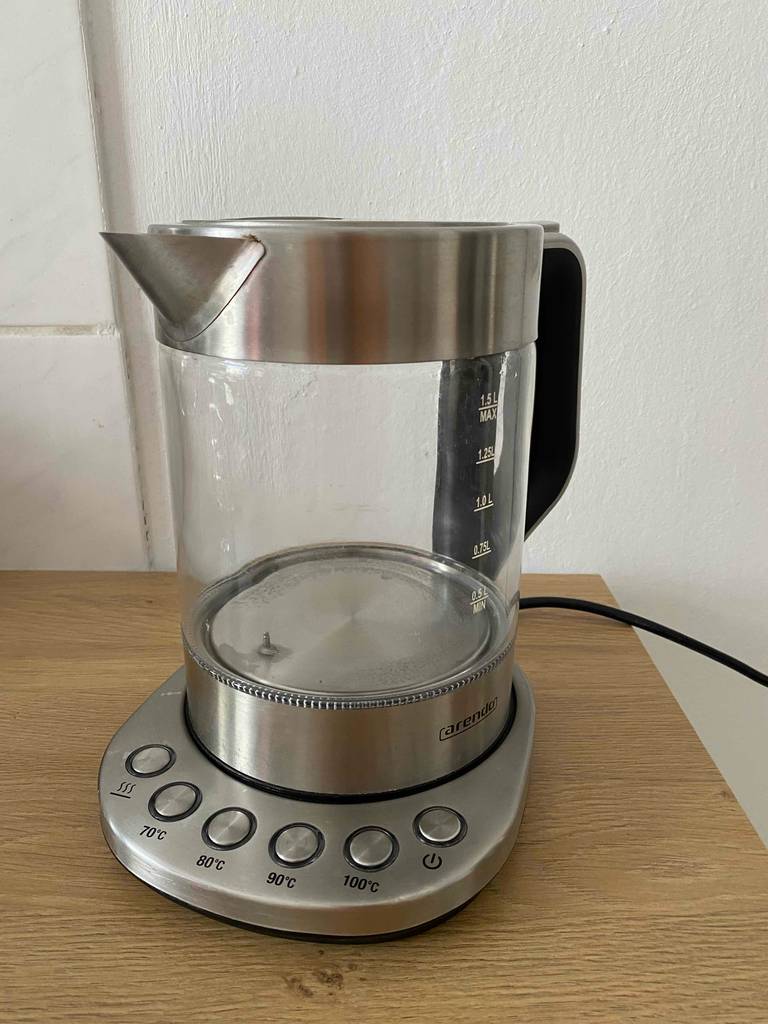 Wasserkocher 1,5 Liter Test: Ein Modell der Marke Arendo mit unterschiedlichen Heizstufen-Tasten auf der Basis steht auf einer Holzoberfläche.