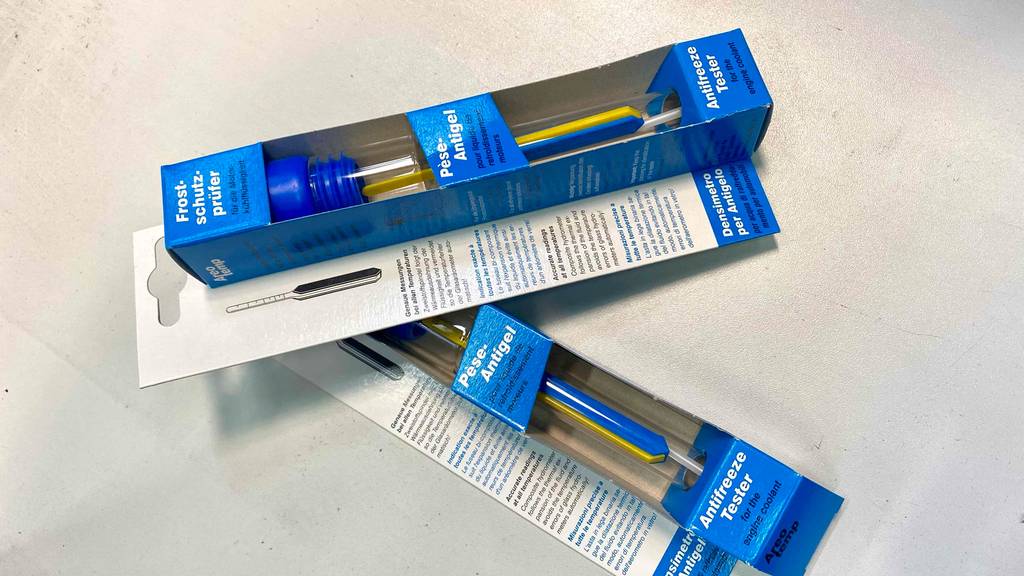 Zwei blaue Verpackungen mit Frostschutzprüfer im Test liegen schräg übereinander auf einem weißen Untergrund.