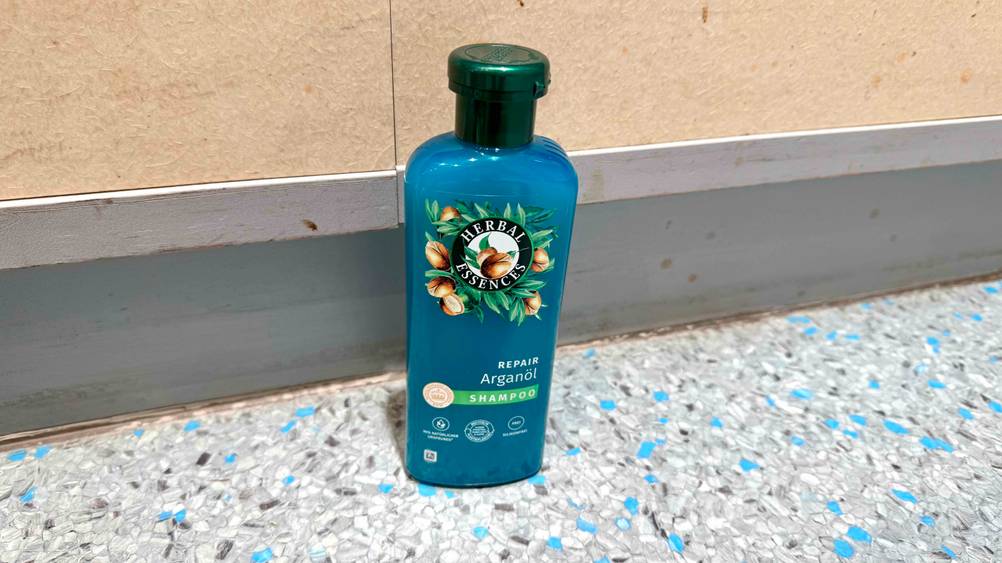 Vor einer Wand steht eine Flasche des Argan-Shampoos im Test.