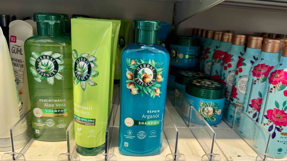 Eine Flasche des getesteten Argan-Shampoos steht mit mehreren anderen Produkten in einem Regal.