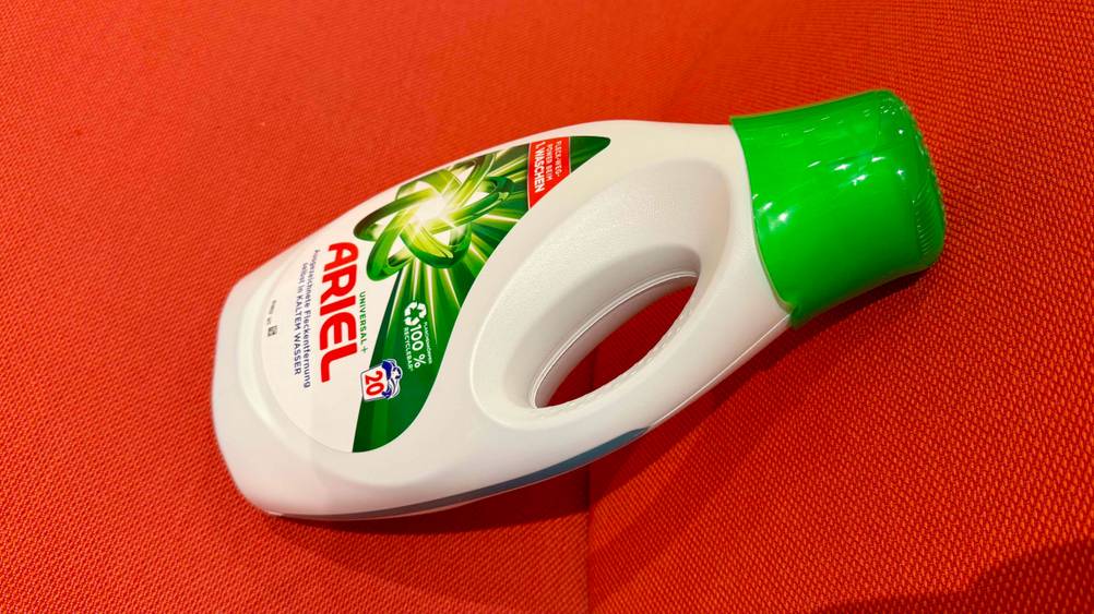 Seitenansicht einer Flasche des getesteten Ariel-Waschmittels auf einem roten Polster.