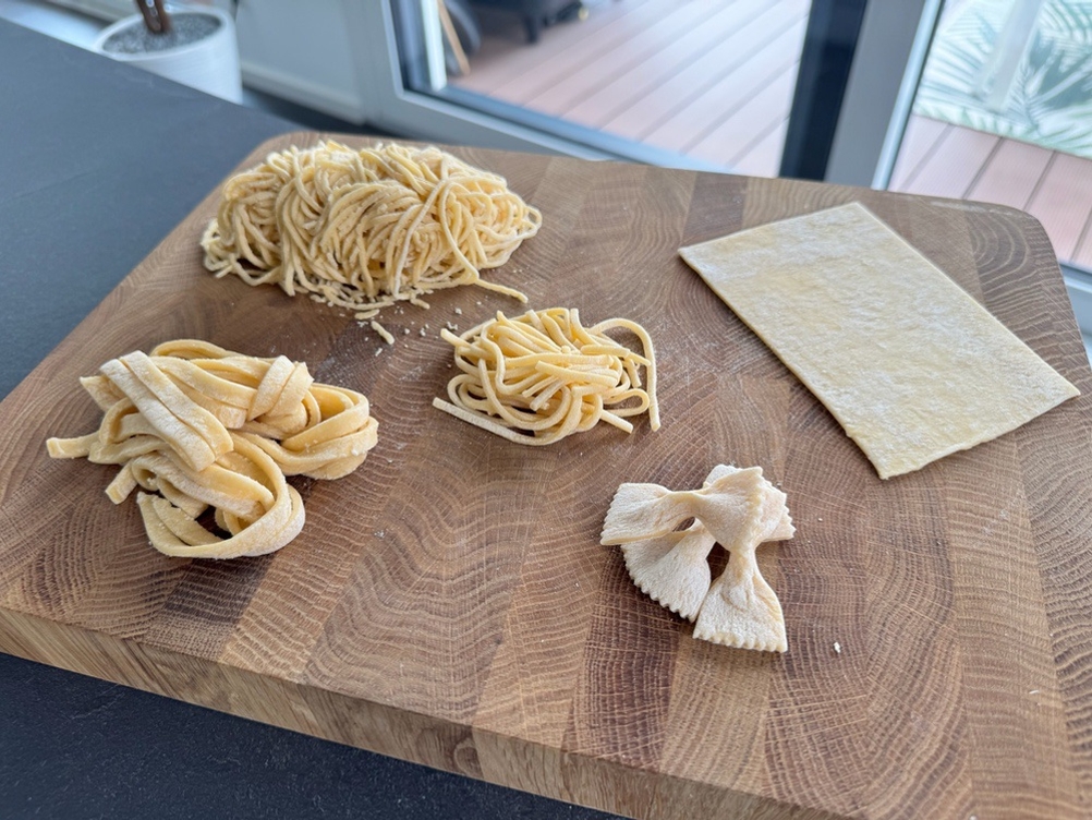 Fünf verschiedene Nudelsorten aus der Ariete Pastamatic 1593 liegen auf einem Holzbrett