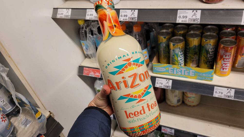 Eine Hand hält eine Flasche des Arizona-Eistees im Test vor ein Regal.