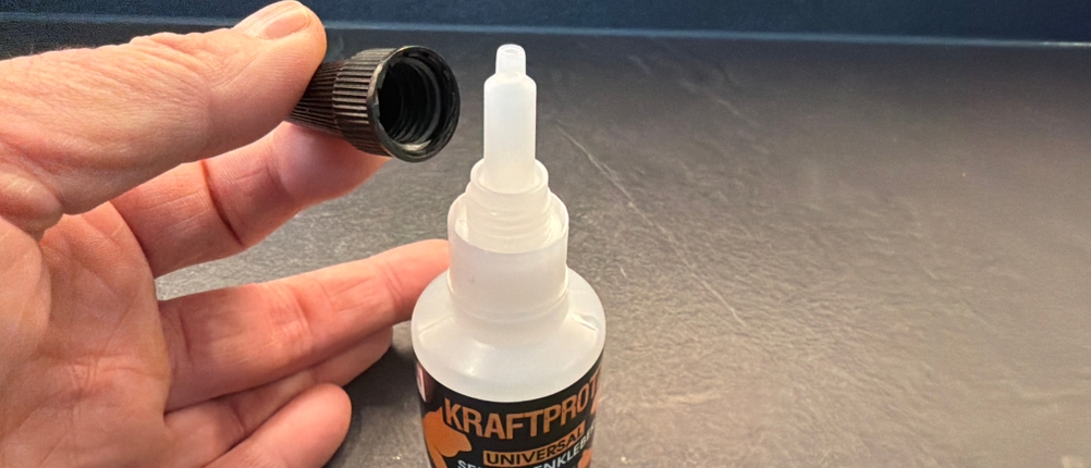 Eine Hand hält den abgeschraubten Deckel vom Arka-Sekundenkleber-extra-stark-Gel fest
