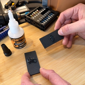 Zwei Plastikstücke mit dem Arka-Sekundenkleber-extra-stark-Gel werden von zwei Händen festgehalten