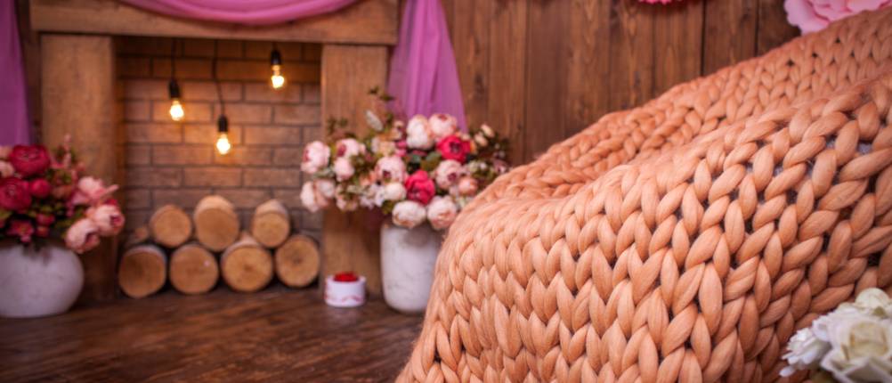 Armstrick-Wolle-Test: apricotfarbene armgestrickte decke vor einem gemütlichen Hintergrund