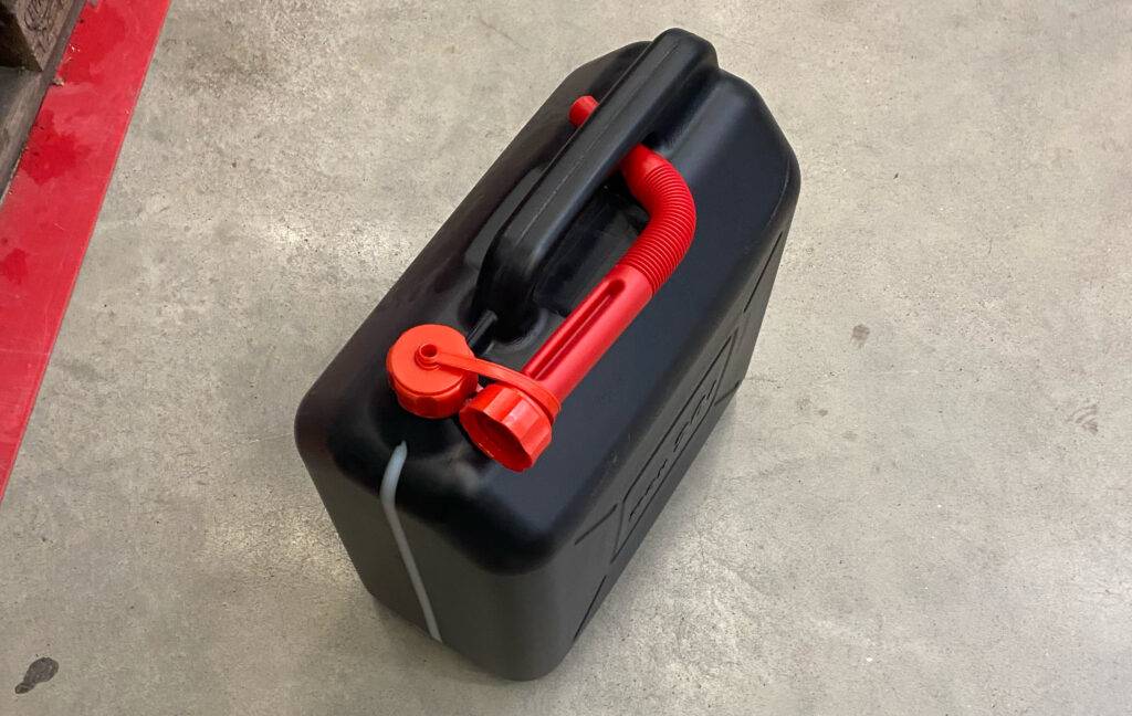Ansicht von oben auf einen schwarzen getesteten Benzinkanister inklusive rotem Einfüll-Aufsatz.
