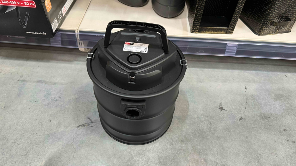 Aschesauger getestet: Ein Gerät von schräg oben auf einem Betonboden vor einem Regal.