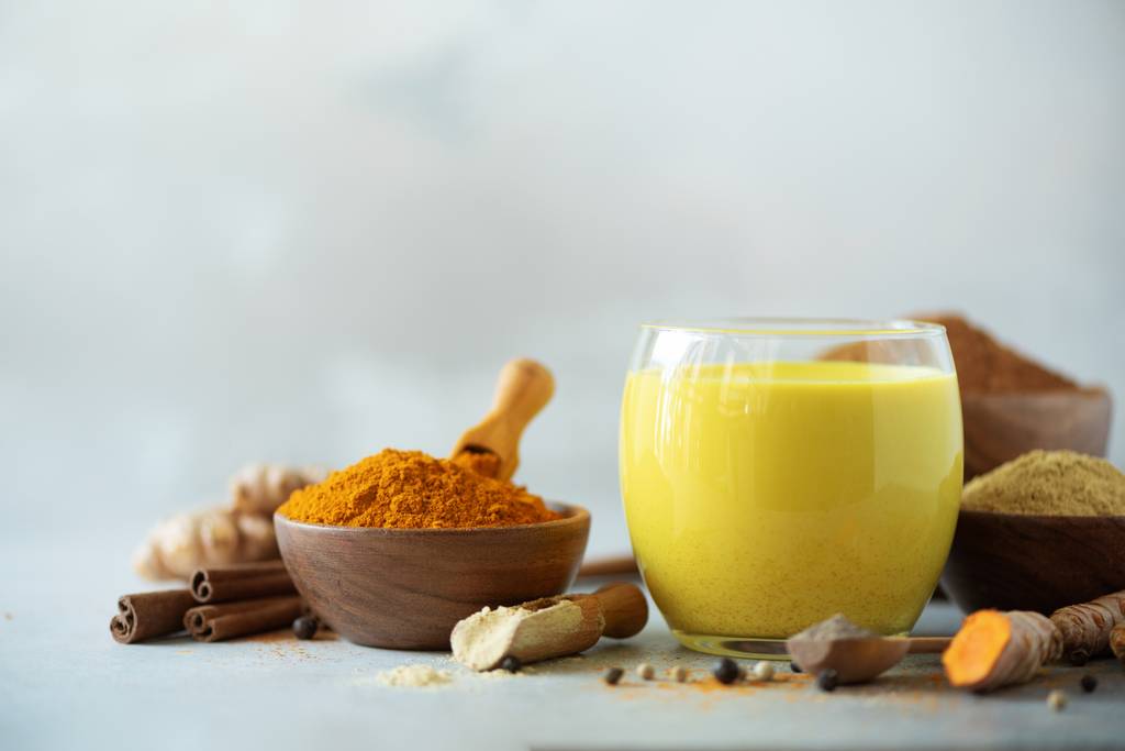 Ashwagandha-Pulver-Test: Auf einer Küchenfläche steht ein Glas mit goldener Milch und diversen Gewürzen. 