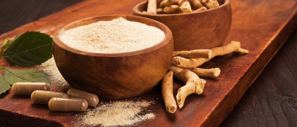 Ashwagandha-Pulver-Test: Auf einem Holzbrett stehen zwei Holzschalen mit Ashwagandha. 