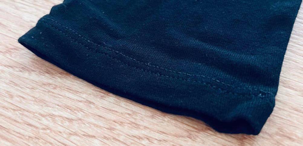 Lange Unterhosen für Damen im Test: elastischer Saum eines schwarzen Hosenbeins auf einer Holzoberfläche.