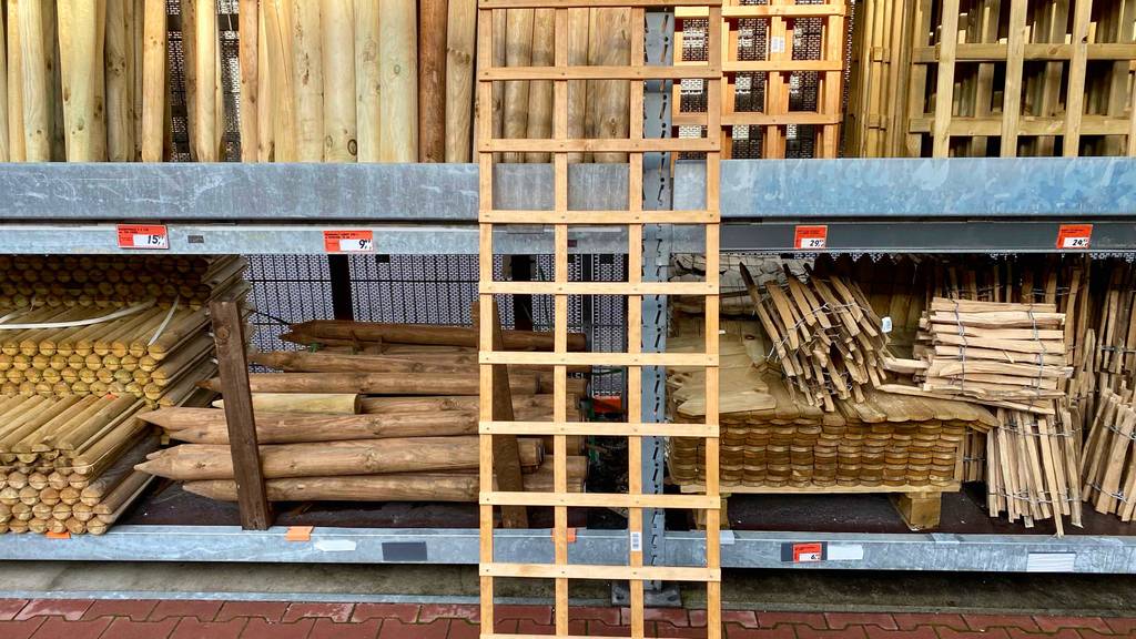 Ein Rankgitter aus Holz steht zum Testen vor einem riesigen Verkaufsregal mit anderen Holzmaterialien.